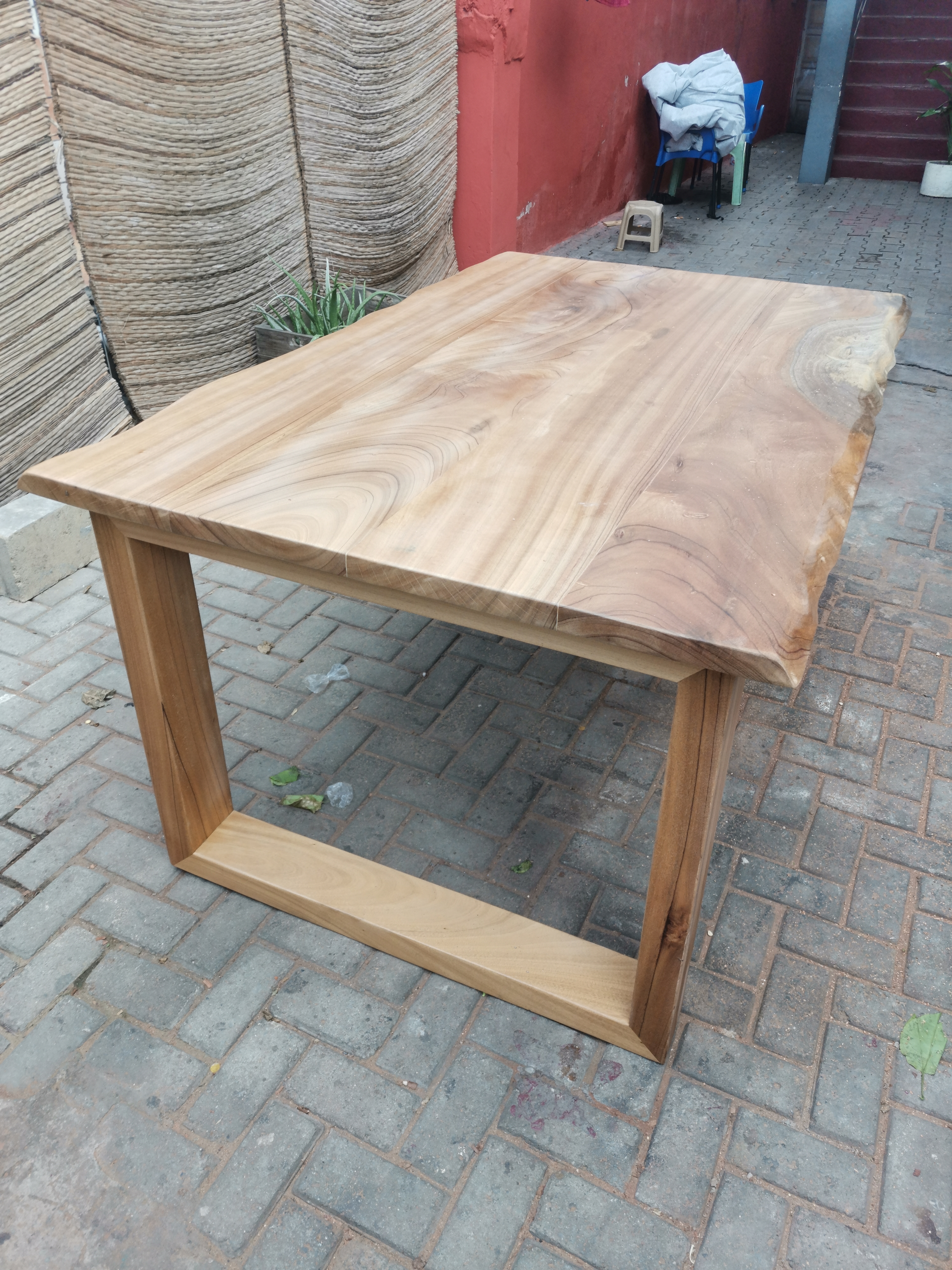 Afromosia live-edge dining table — second outdoor shot showing full form
