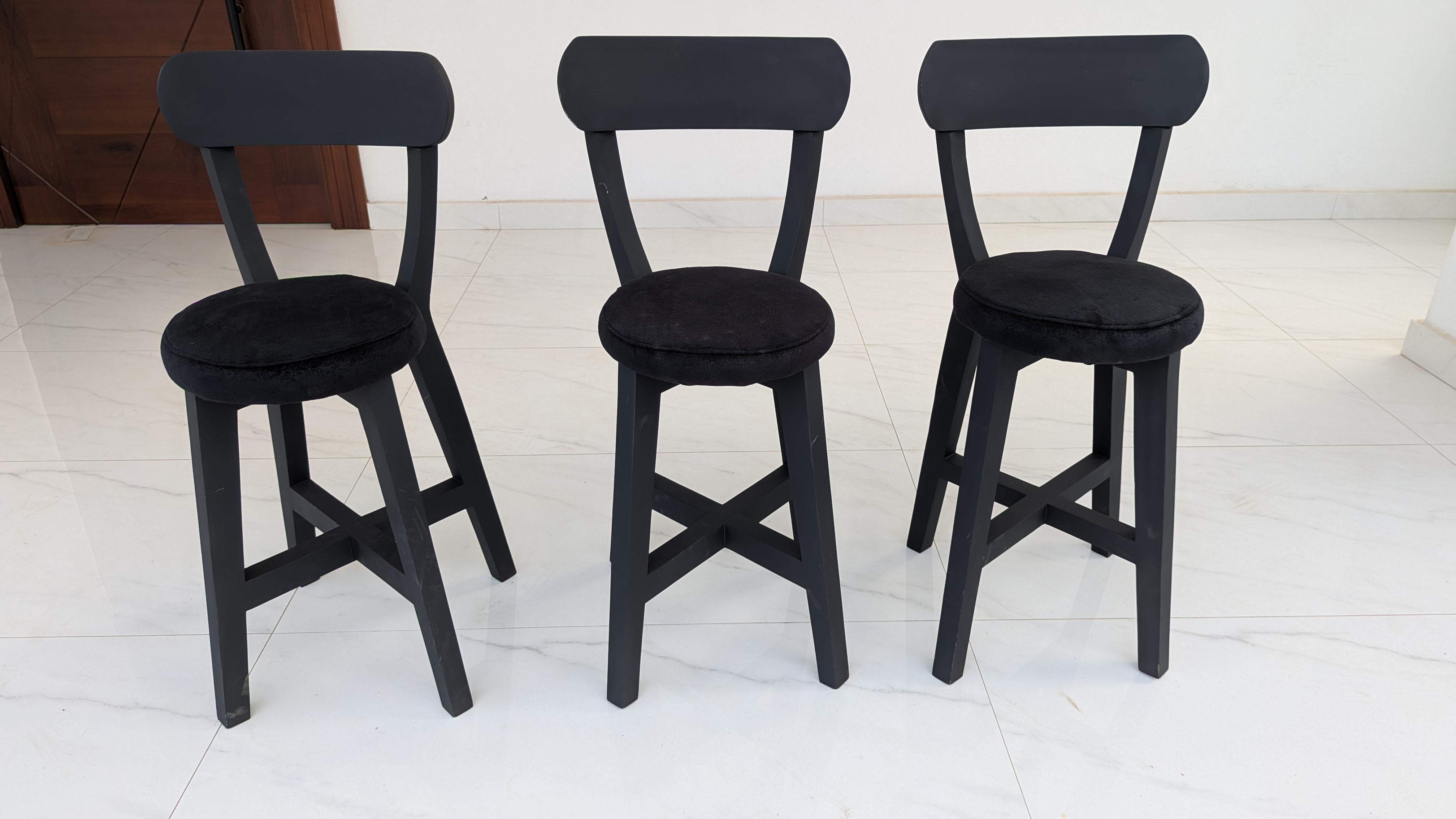 Three matching solid wood bar stools with dark velvet upholstered seats — built by Neewoody for a private residence in Dome, Accra