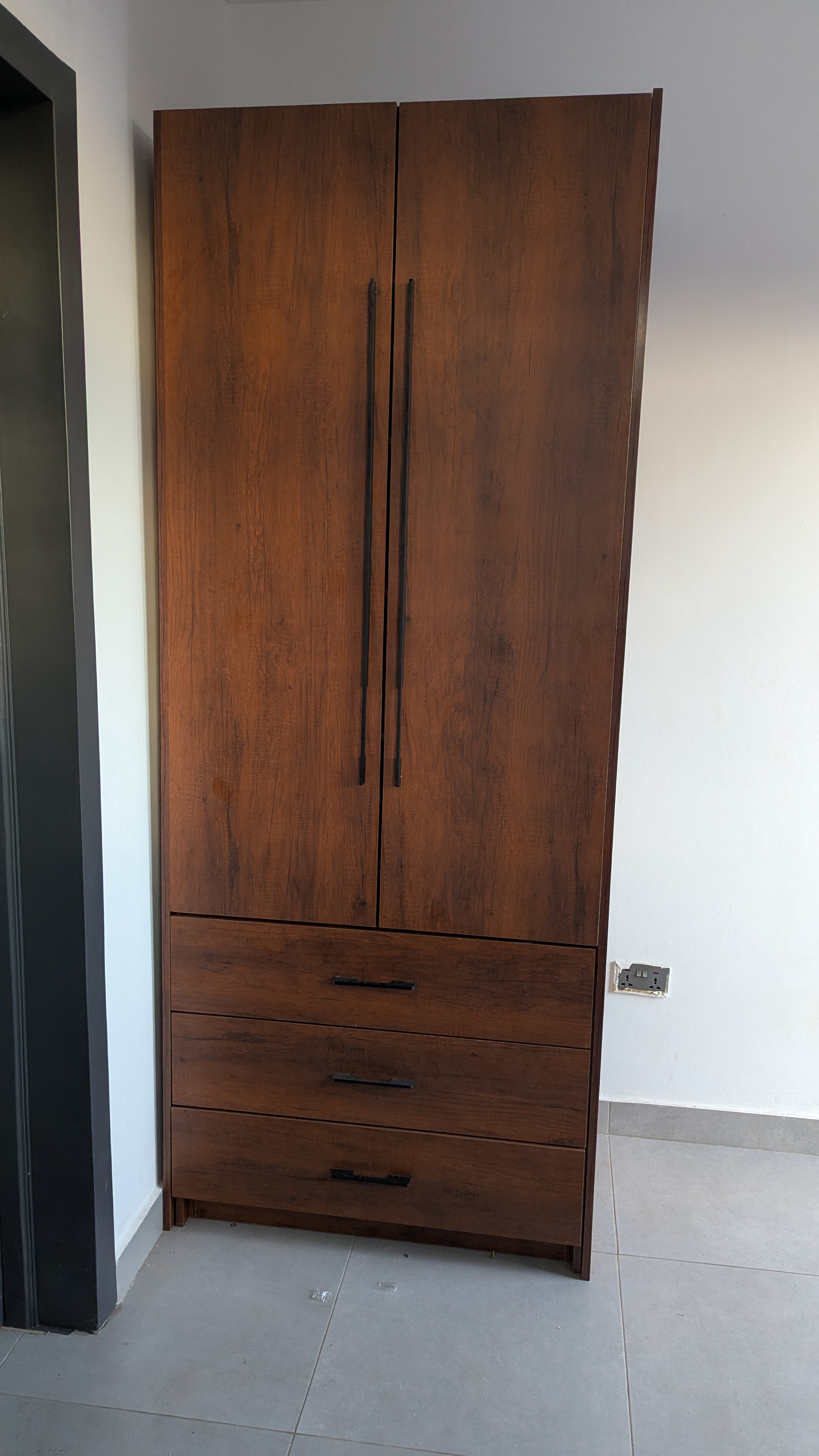 Full-height fitted wardrobe in dark laminate with three drawers and matte black bar handles — Dome, Accra