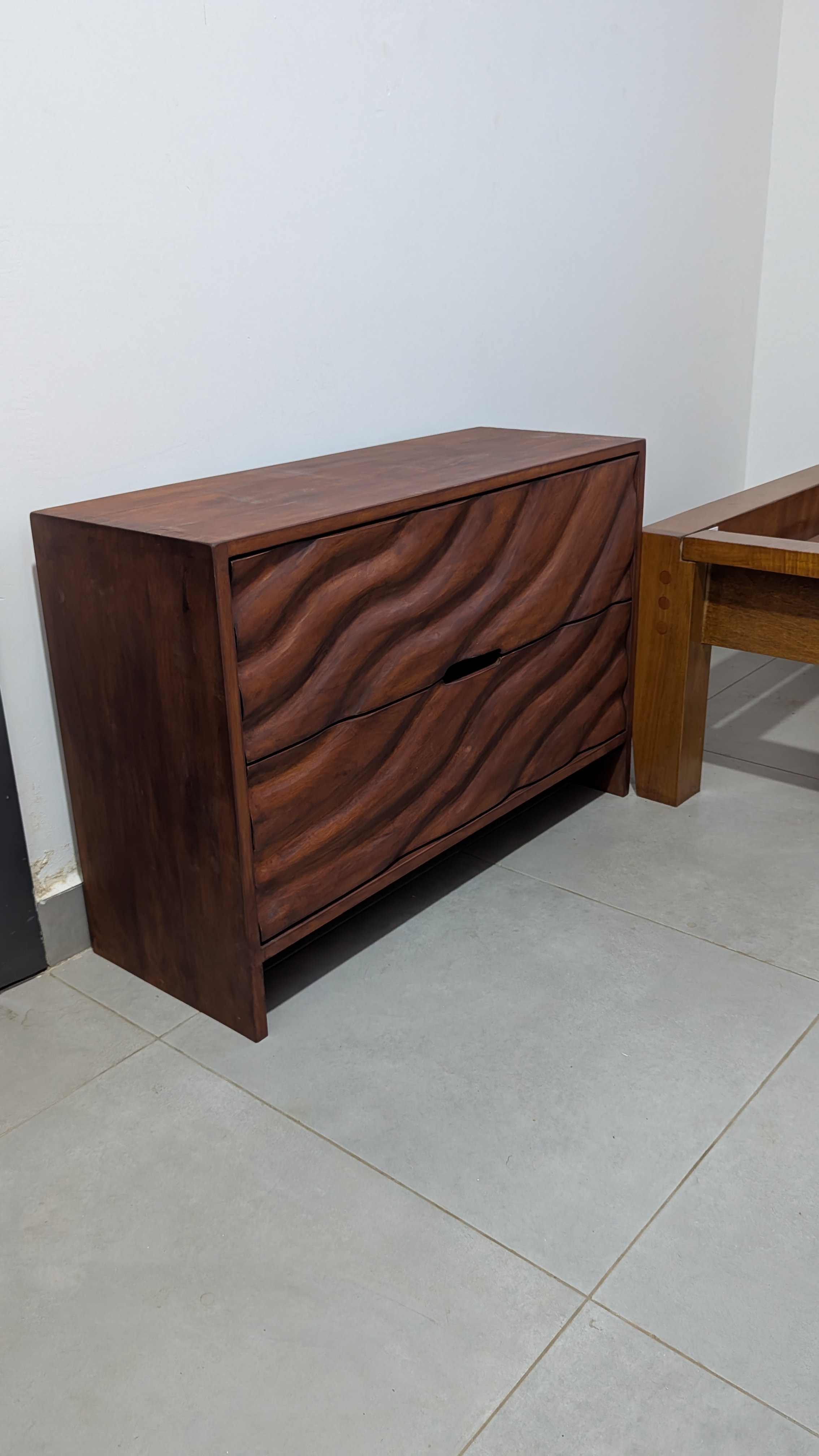 Wave-carved Guarea chest of drawers — second angle showing continuous carving across all drawer fronts