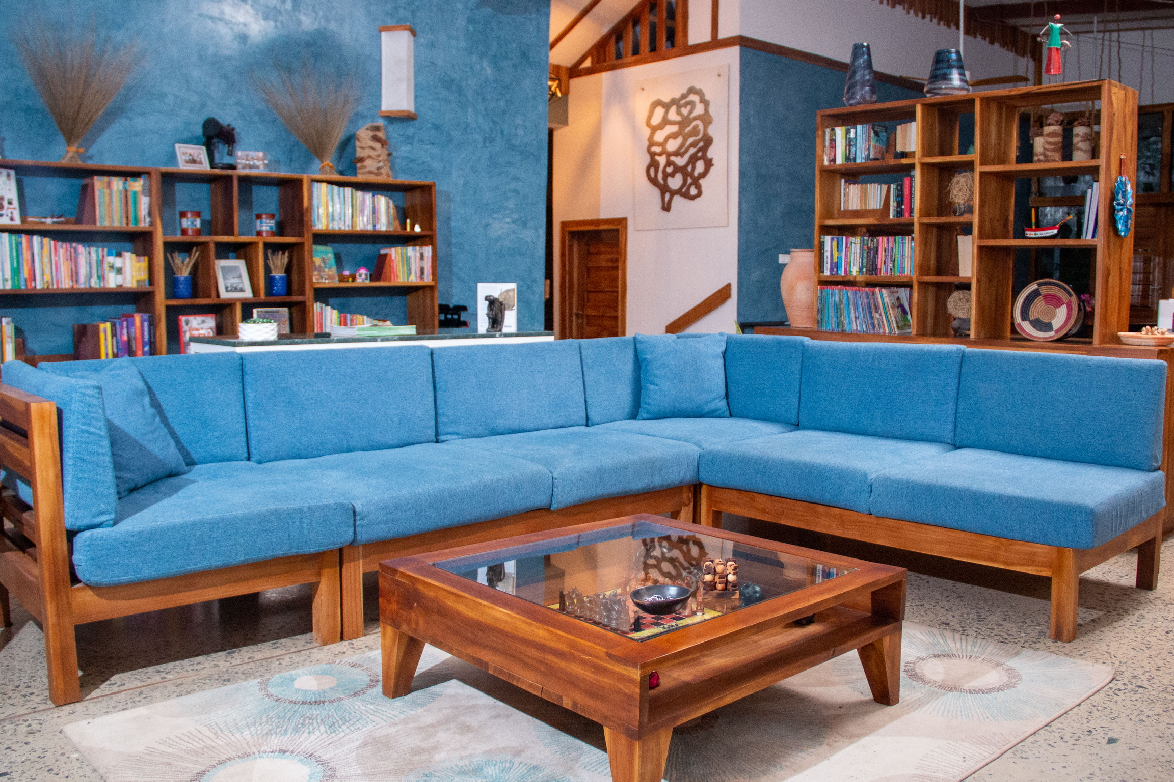 L-shaped teak sofa and bookshelves in the main living room at Sage Centre